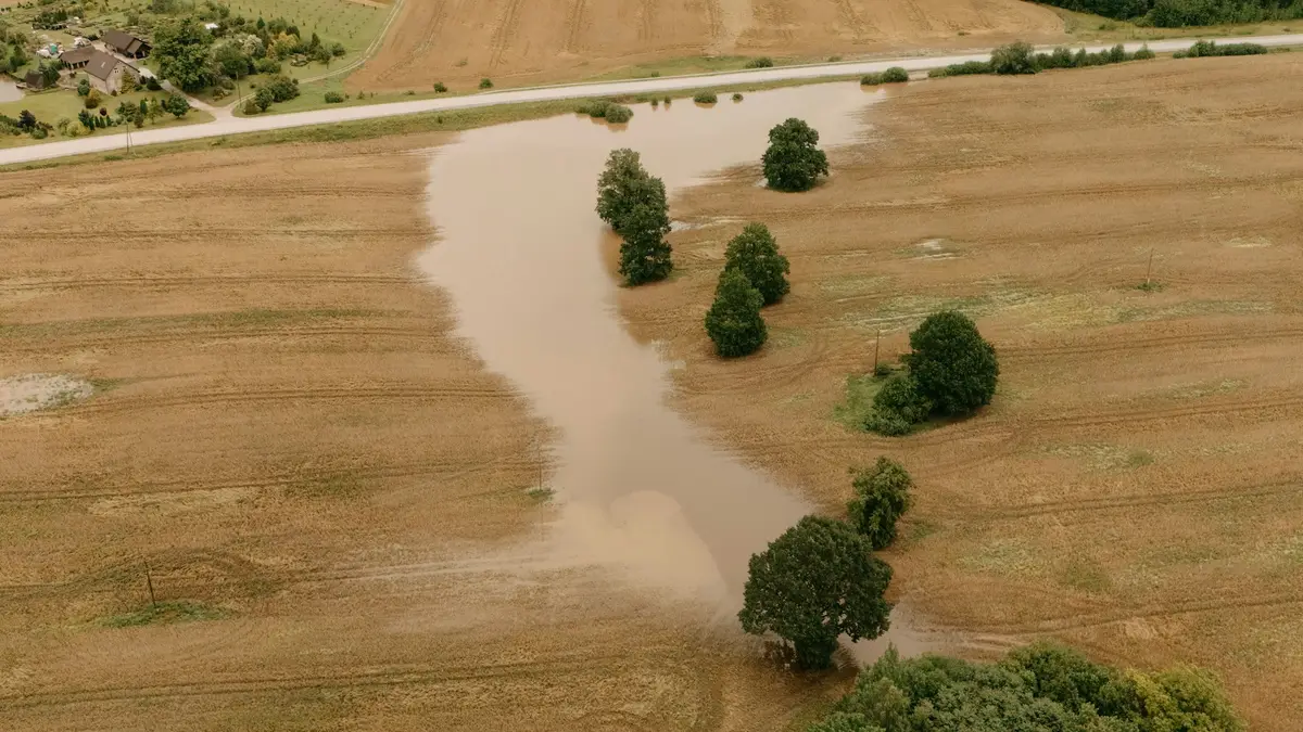 Aerial view of brown floodwater spreading across flat farm fields