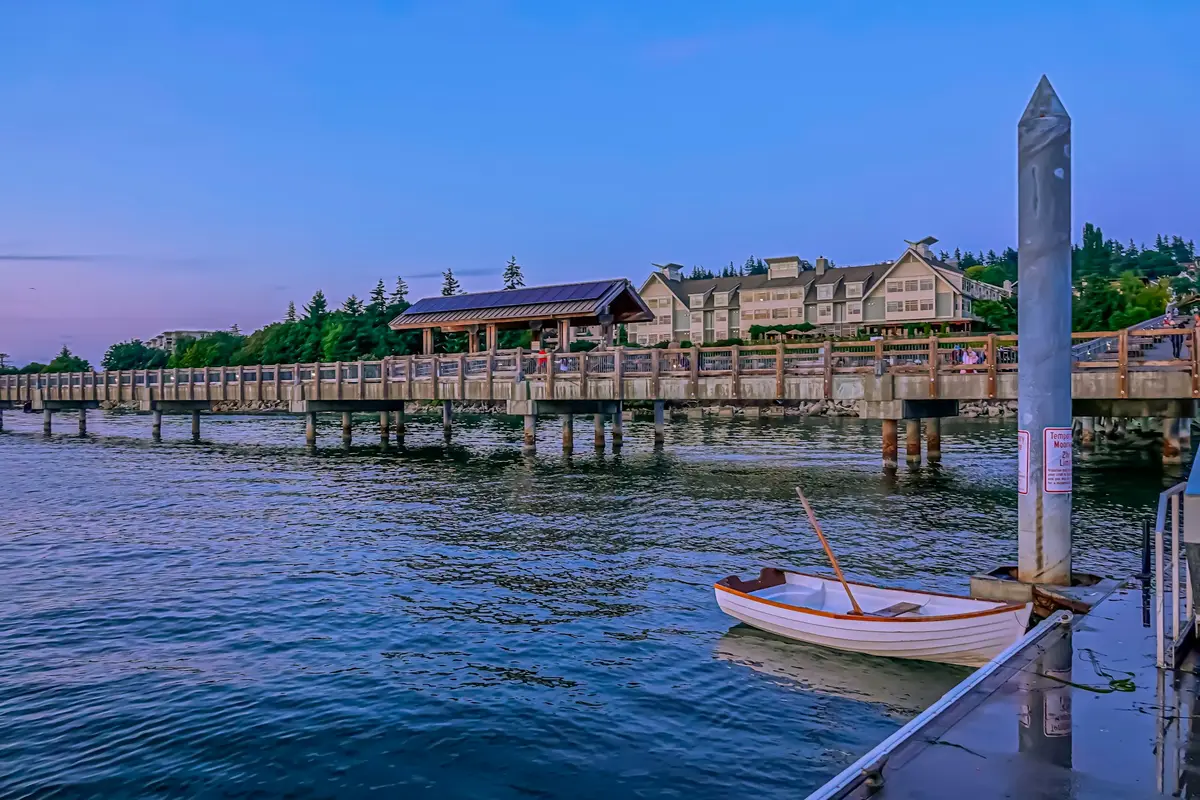 A wooden boardwalk and a small rowboat on Bellingham Bay at dusk